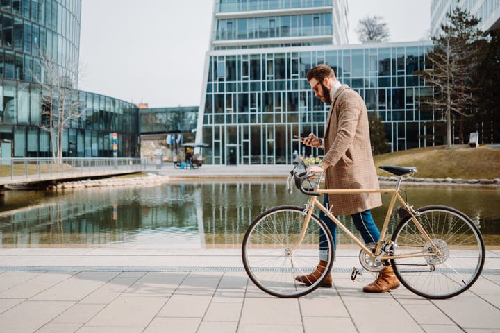 Modern Businessman Checks Phone During Urban Bicycle Commute