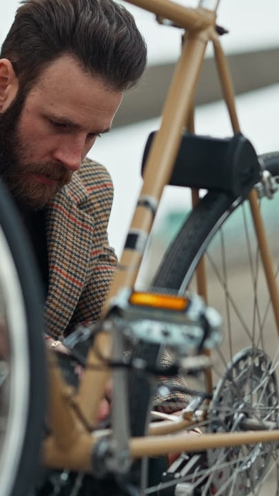 Focused Businessman Fixes His Bicycle On a Cloudy Day