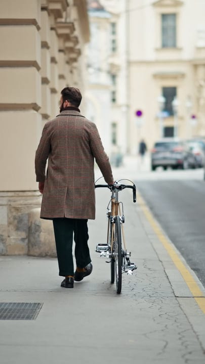 Urban Businessman Strolls with Bicycle on City Street