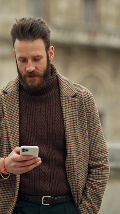 Bearded Businessman Engages With Smartphone on City Street