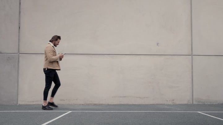 Businessman Strolls Through Urban Landscape Checking Phone