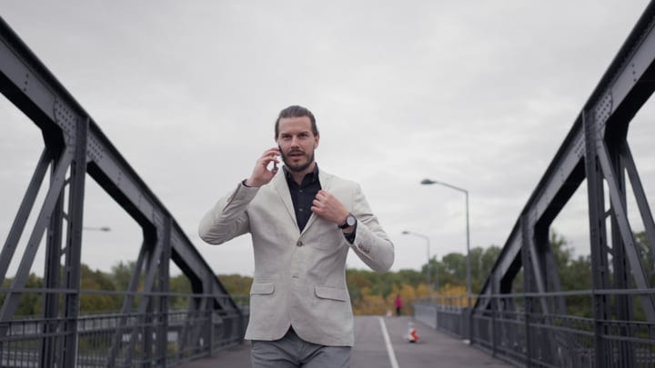 Businessman Engages On Phone During Urban Bridge Walk