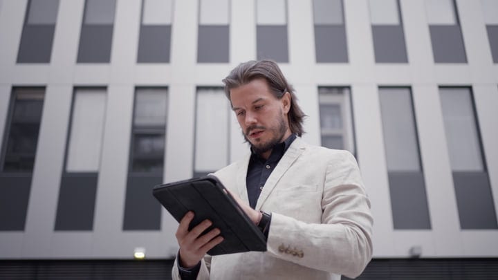 Focused Businessman Engages With Tablet in Cityscape