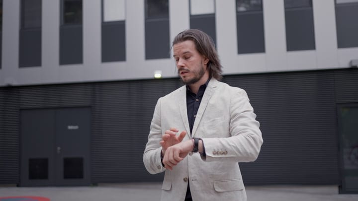 Businessman Checks Time While Strolling Through Modern Cityscape