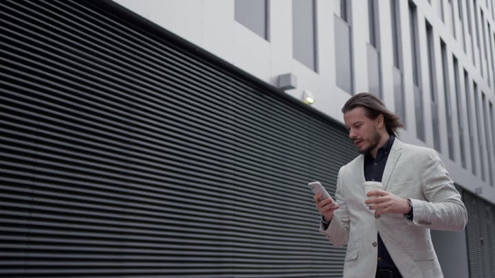 Focused Businessman Checks Phone During His City Walk