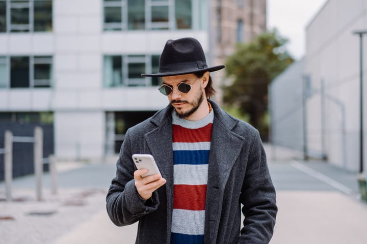 Stylish Businessman Browses Phone On Urban Stroll
