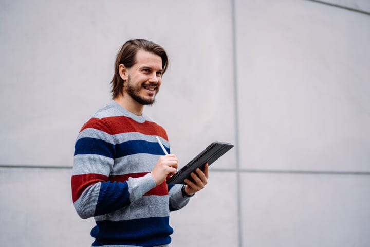 Smiling Businessman Engages with Tablet During Urban Walk