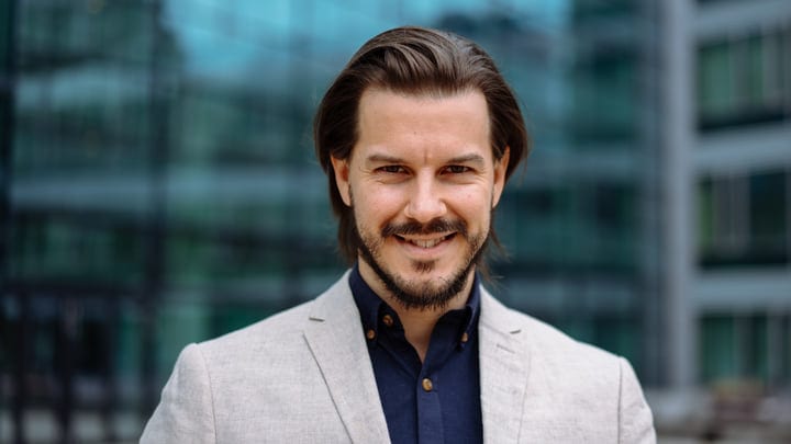 Confident Businessman Smiling Against Modern Glass Architecture
