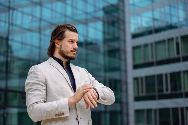 Confident Businessman Checks Time Amidst Cityscape Reflections