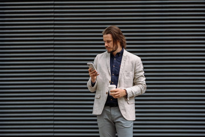 Confident Businessman Checks Phone Against Urban Backdrop