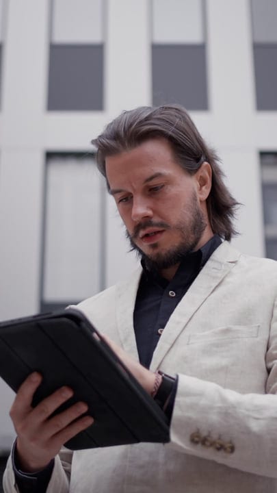 Focused Businessman Reads Tablet in Urban Setting