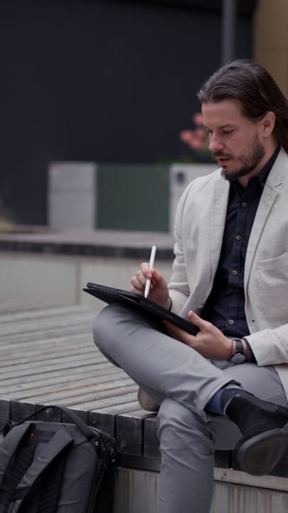 Businessman Ponders Ideas With A Pen And Tablet Outdoors