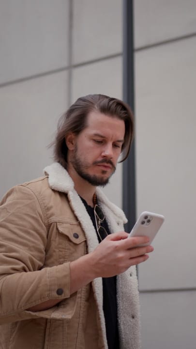 Contemplative Stroll With Phone In Hand Through City Streets